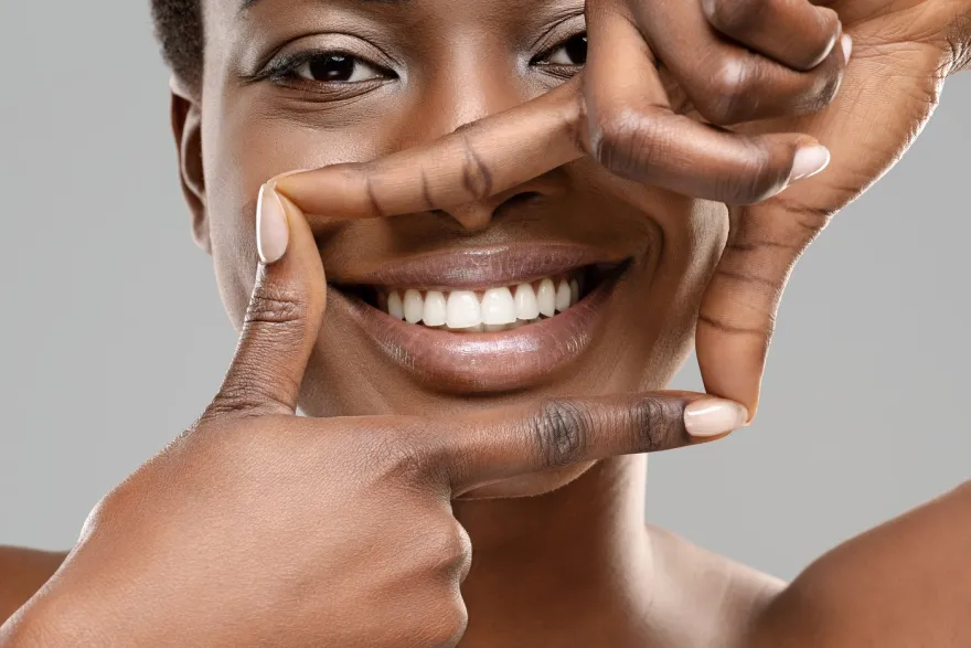 A woman framing her smile with both hands.