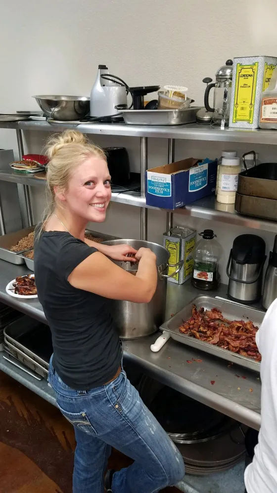 A staff member flexing beside catering trays in a kitchen.
