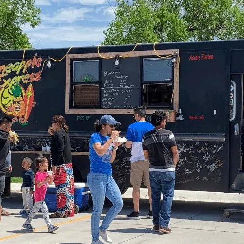 Families queuing at a food truck during a community event.