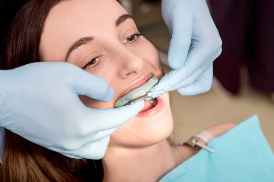 A dental technician holding a mould of a set of teeth.
