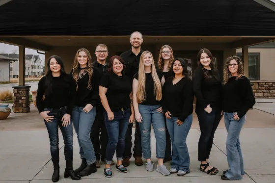 The Scottsbluff Dentist team outside the office, 10 staff members in matching black shirts gathered and smiling.