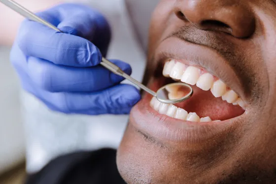 A dentist examines a patient's teeth with a mirror and probe.