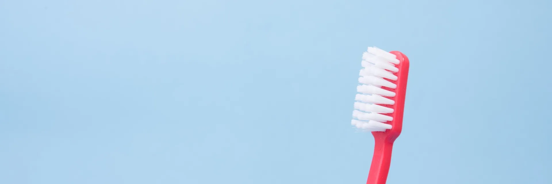 A red toothbrush against a pale blue background.